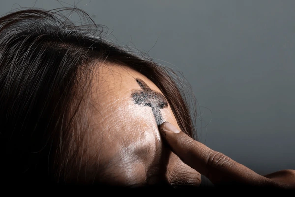 Ashes being applied to someones forehead