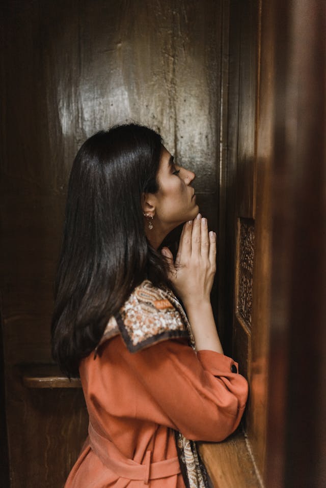 Woman kneeling in a Catholic Confession booth